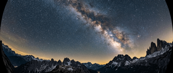 Milky Way galaxy arcing over rocky mountain peaks under a clear night sky filled with stars